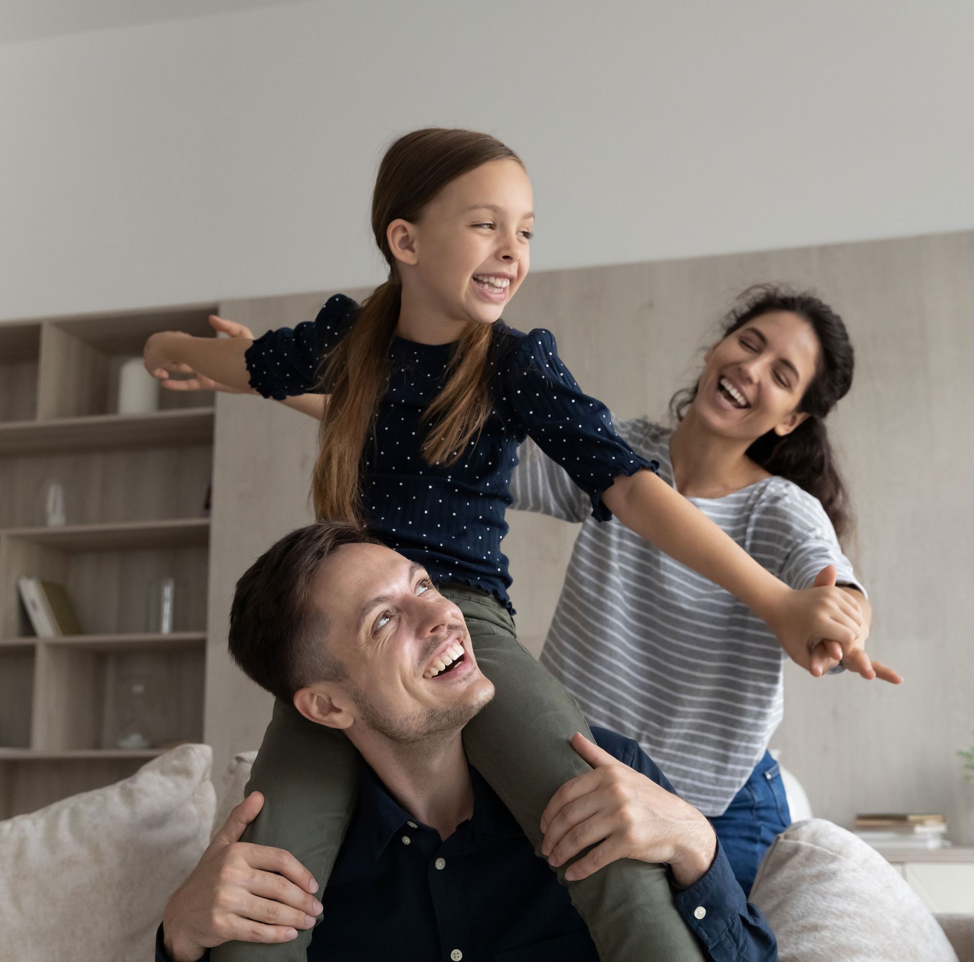 A family is sitting on the floor looking at a laptop computer.