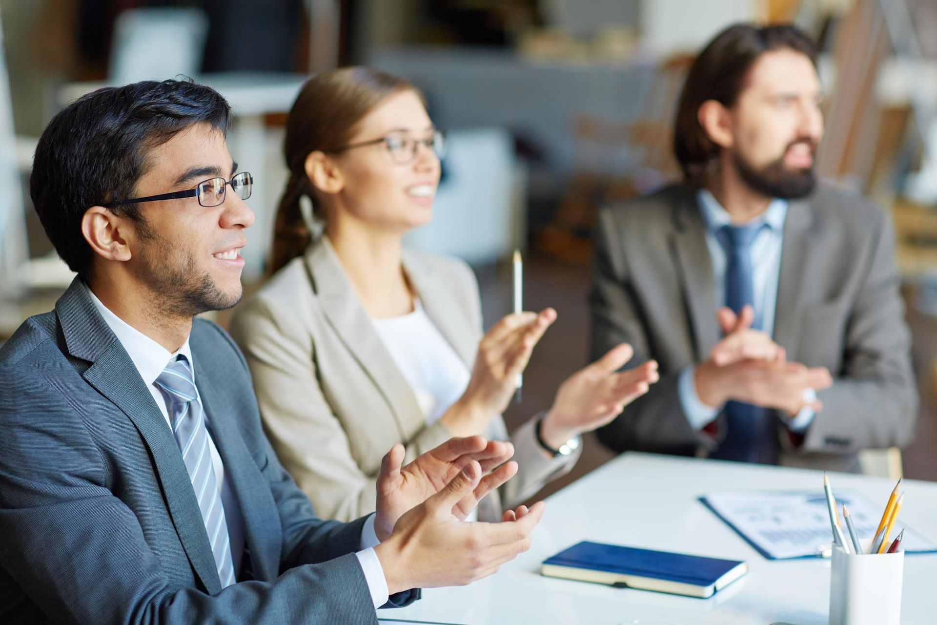 A woman in an apron is holding a tablet in front of a welcome open sign.