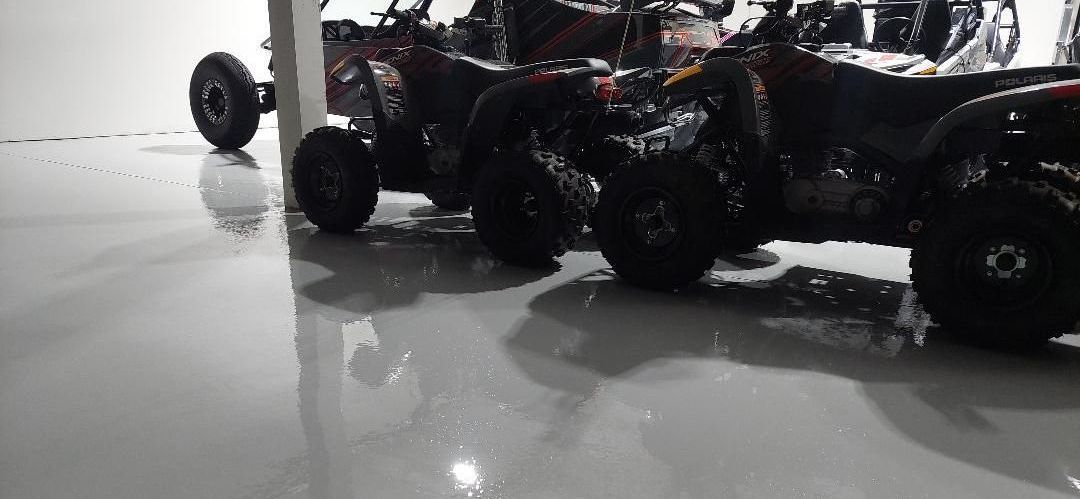 A row of atvs are parked in a garage.