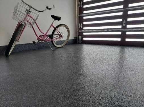 A pink bicycle is parked in a garage next to a garage door.