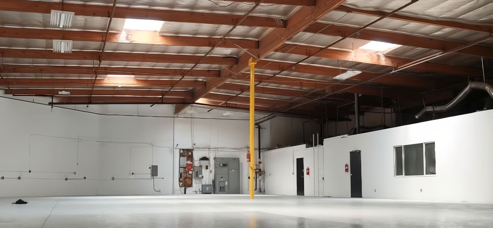 An empty warehouse with white walls and wooden beams