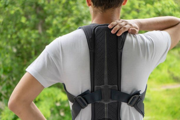 A man is wearing a posture corrector on his back.