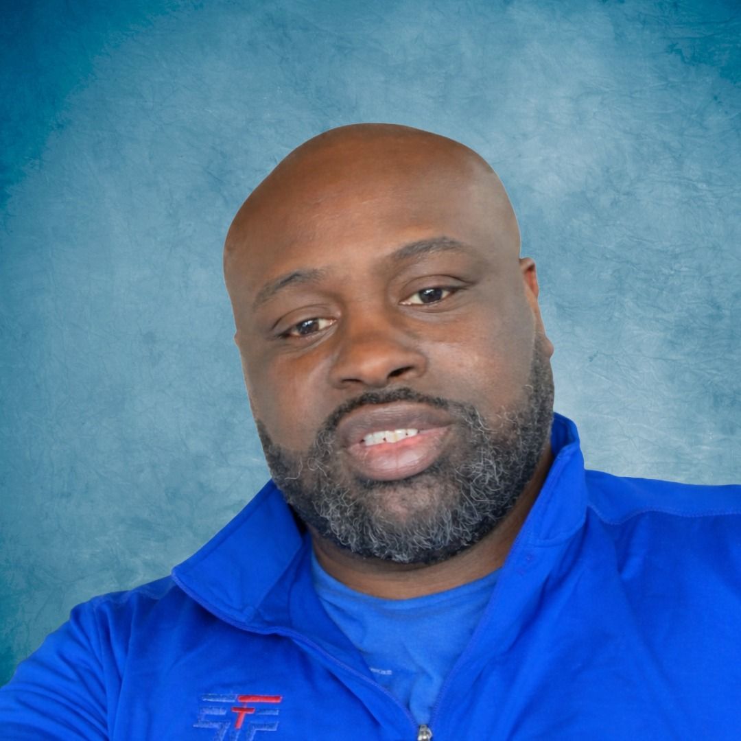 A man  is standing in front of a blue background.