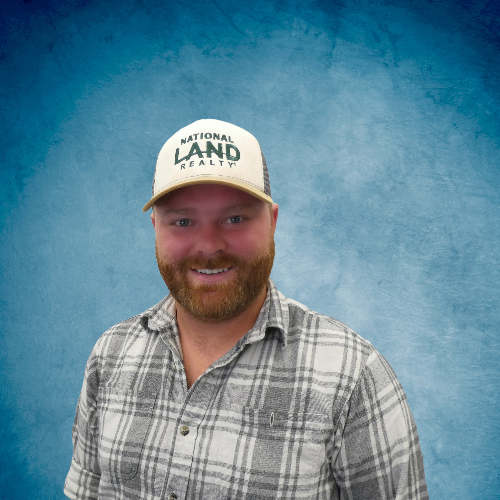 A woman wearing glasses and a green floral shirt is smiling for the camera.