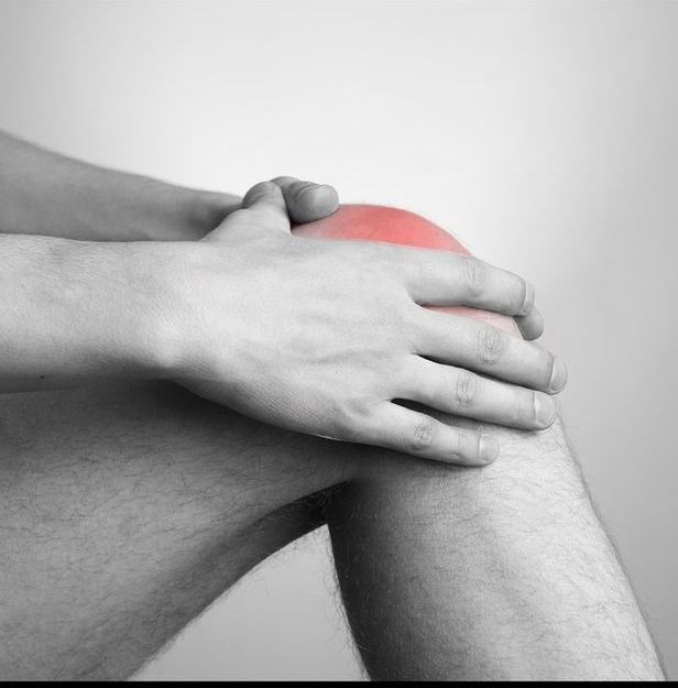 A person is holding their knee in pain.