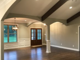 Empty dining room with hardwood floors, arched ceiling beams, and French doors opening to a turquoise pool.