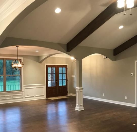 Empty living room with vaulted ceiling, dark wood floors, gray walls, and French doors.