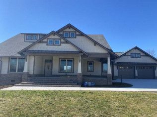 Suburban house with gray roof, front porch, and attached two-car garage under a clear blue sky