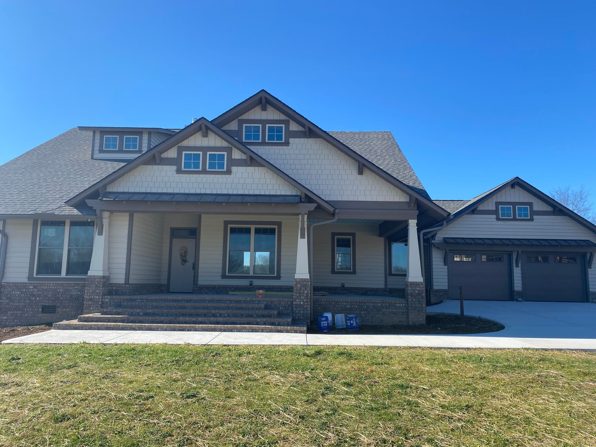 Suburban house with covered front porch, stone accents, and a two-car garage under a blue sky