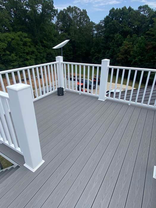 Gray deck with white railings and solar post light overlooking trees