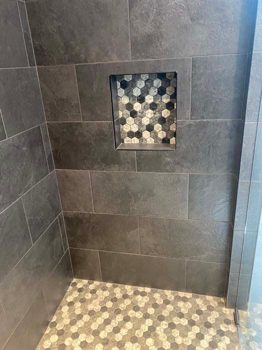 Small gray-tiled shower with a square mosaic shower niche and matching mosaic floor.