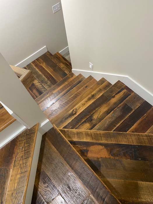 Wooden staircase with dark stained steps and white walls, viewed from above.