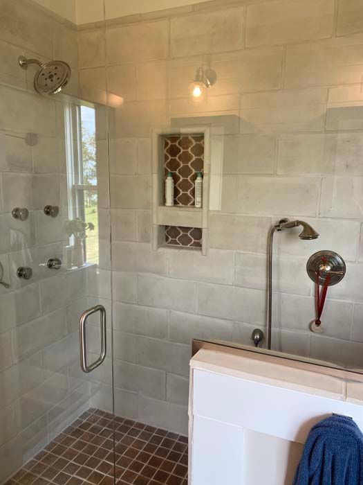 Small tiled bathroom with glass shower, built-in wall niche, and white toilet with a blue towel.