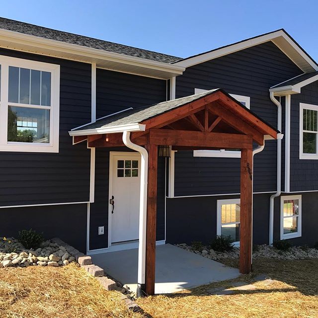 Covered front entry with red wooden porch roof on a dark blue house