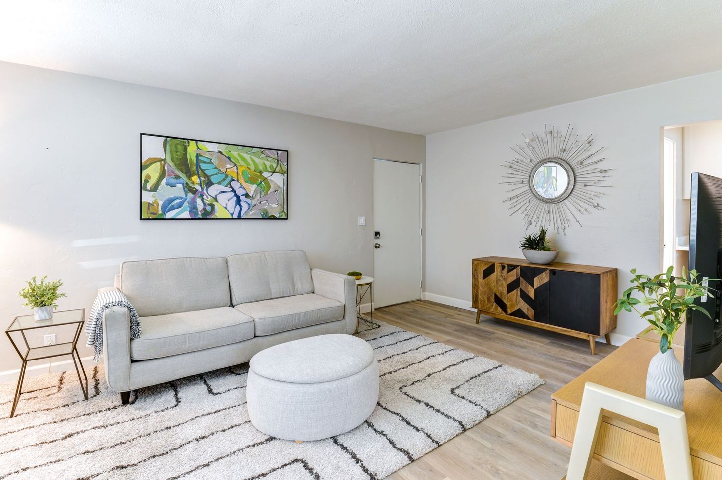 photo showing what the living room could look like when furnished, featuring a glass side table, wall art and a decorative clock