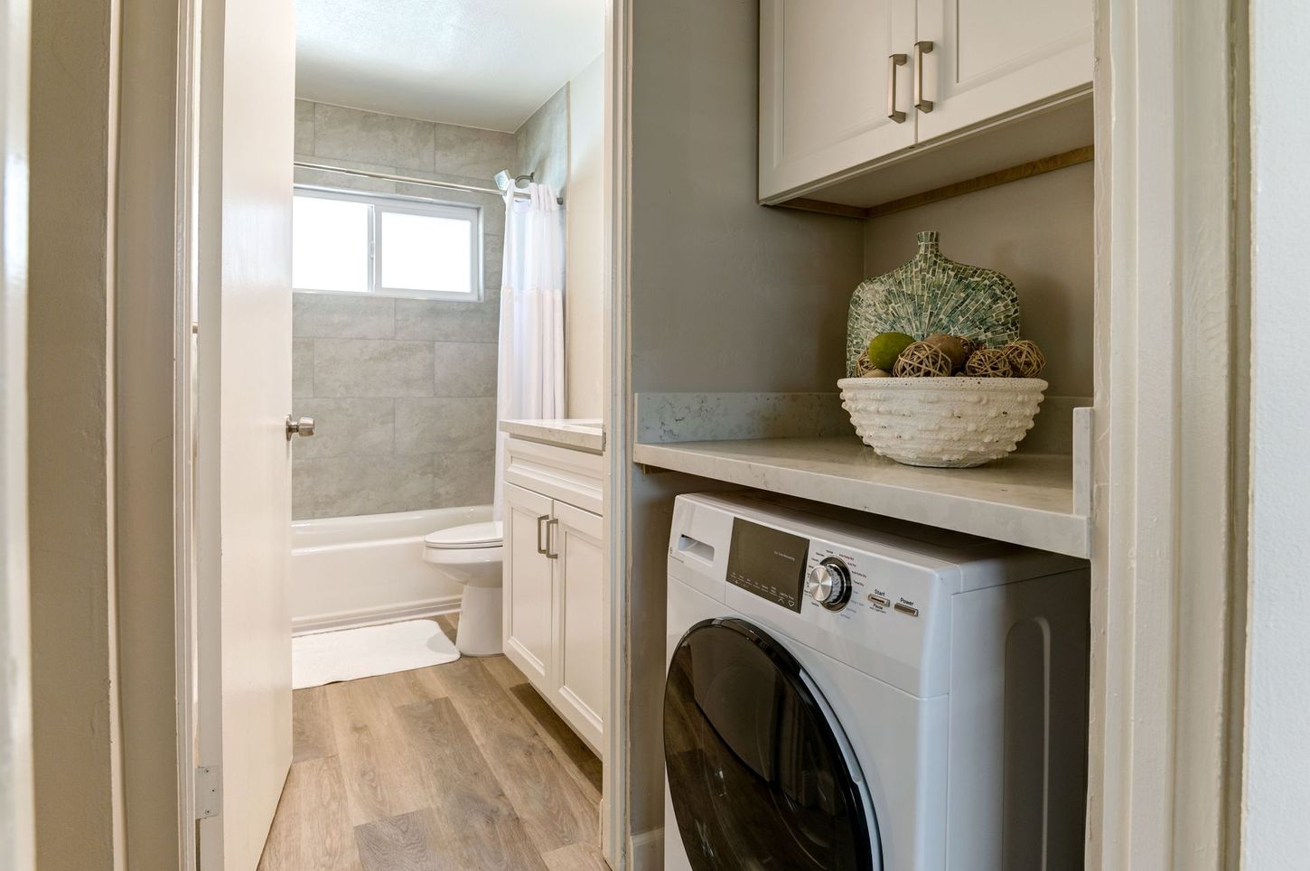 photo showing laundry area with the bathroom in the background