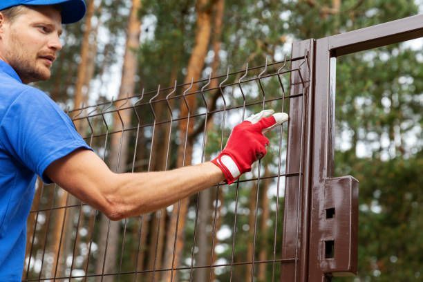 Territory enclosure worker installing metal fence