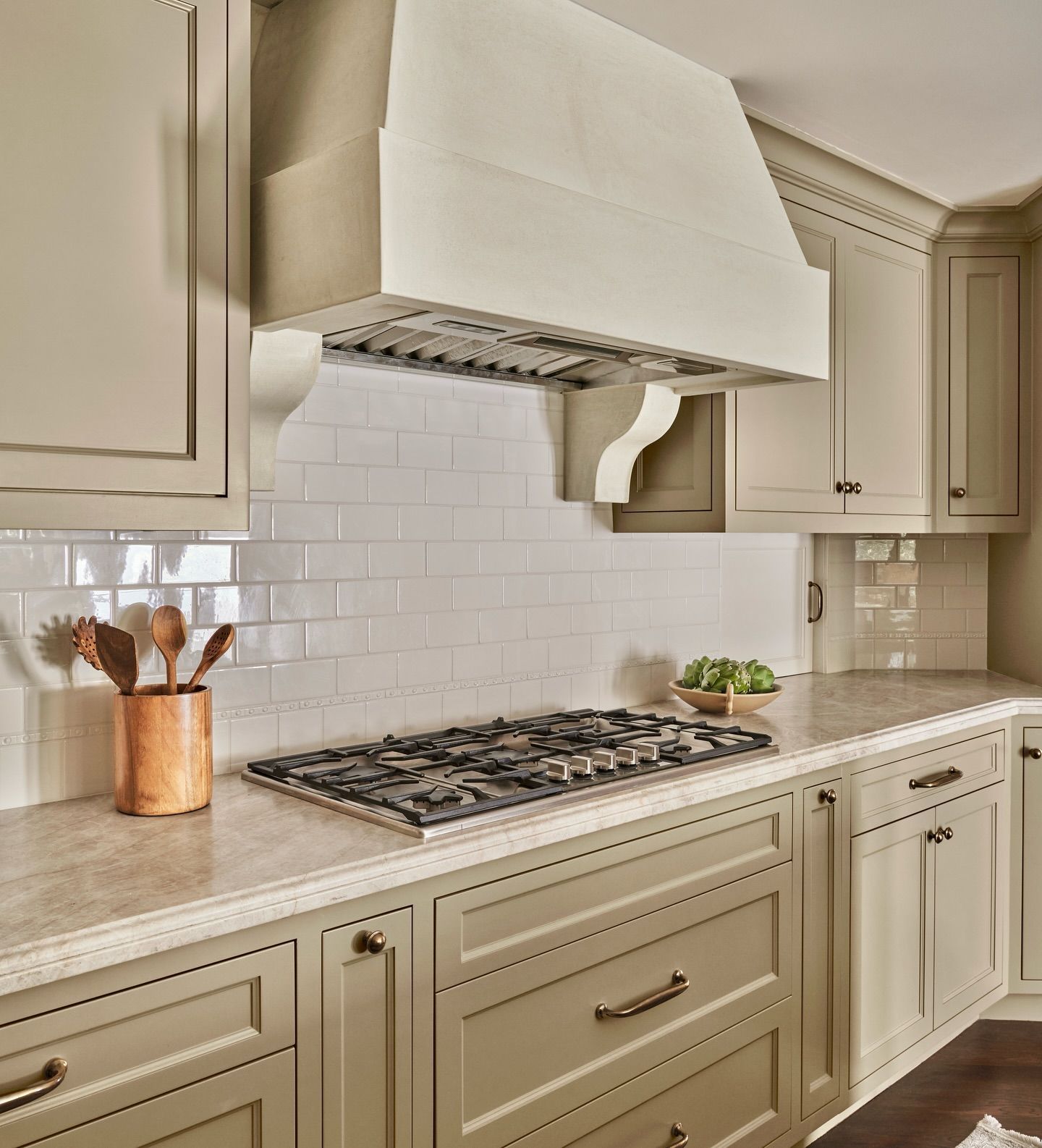 Beige kitchen with stove, white subway tile backsplash, and light wood cabinetry.