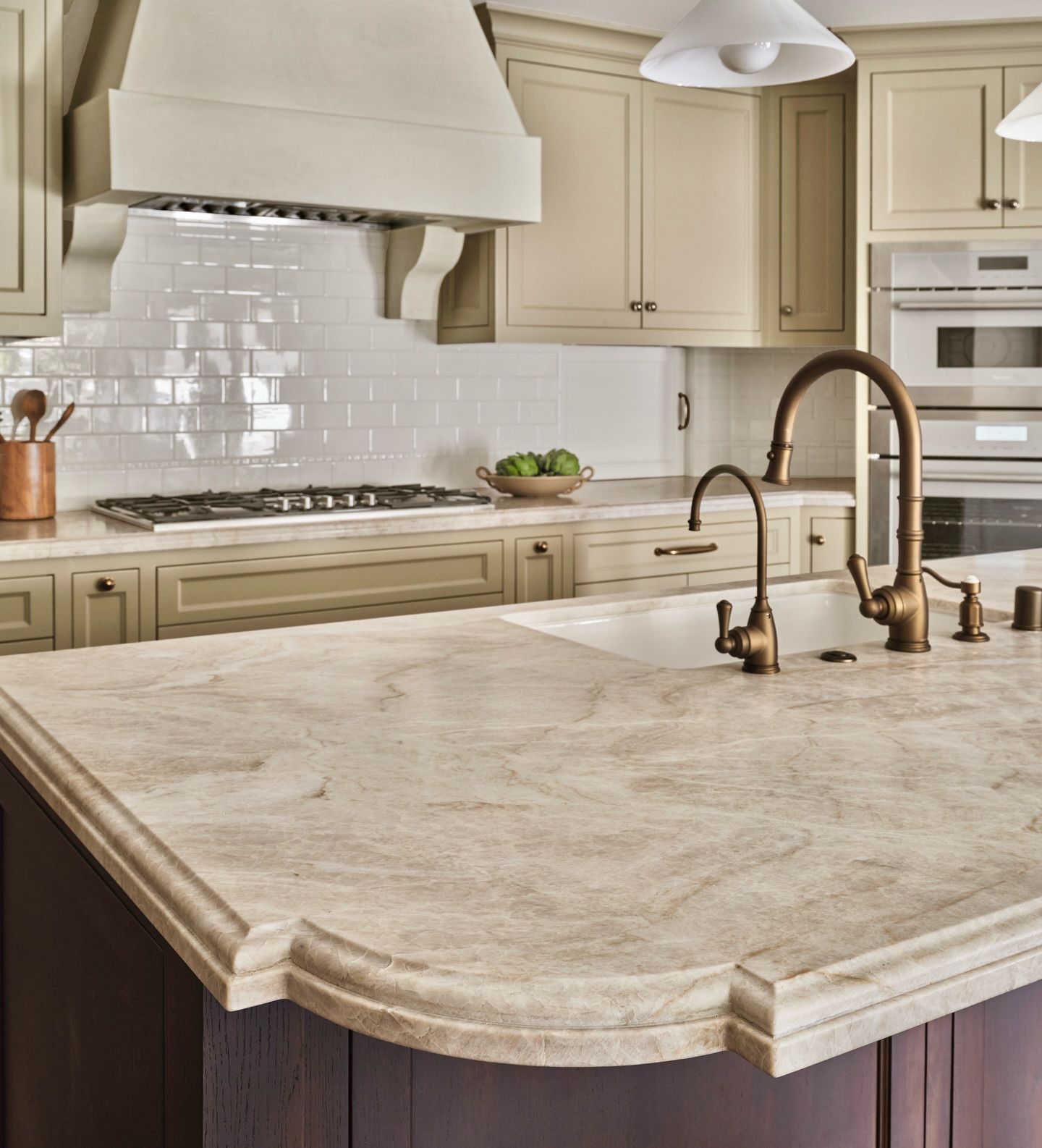 Kitchen with beige cabinets, marble countertops, and bronze faucet.