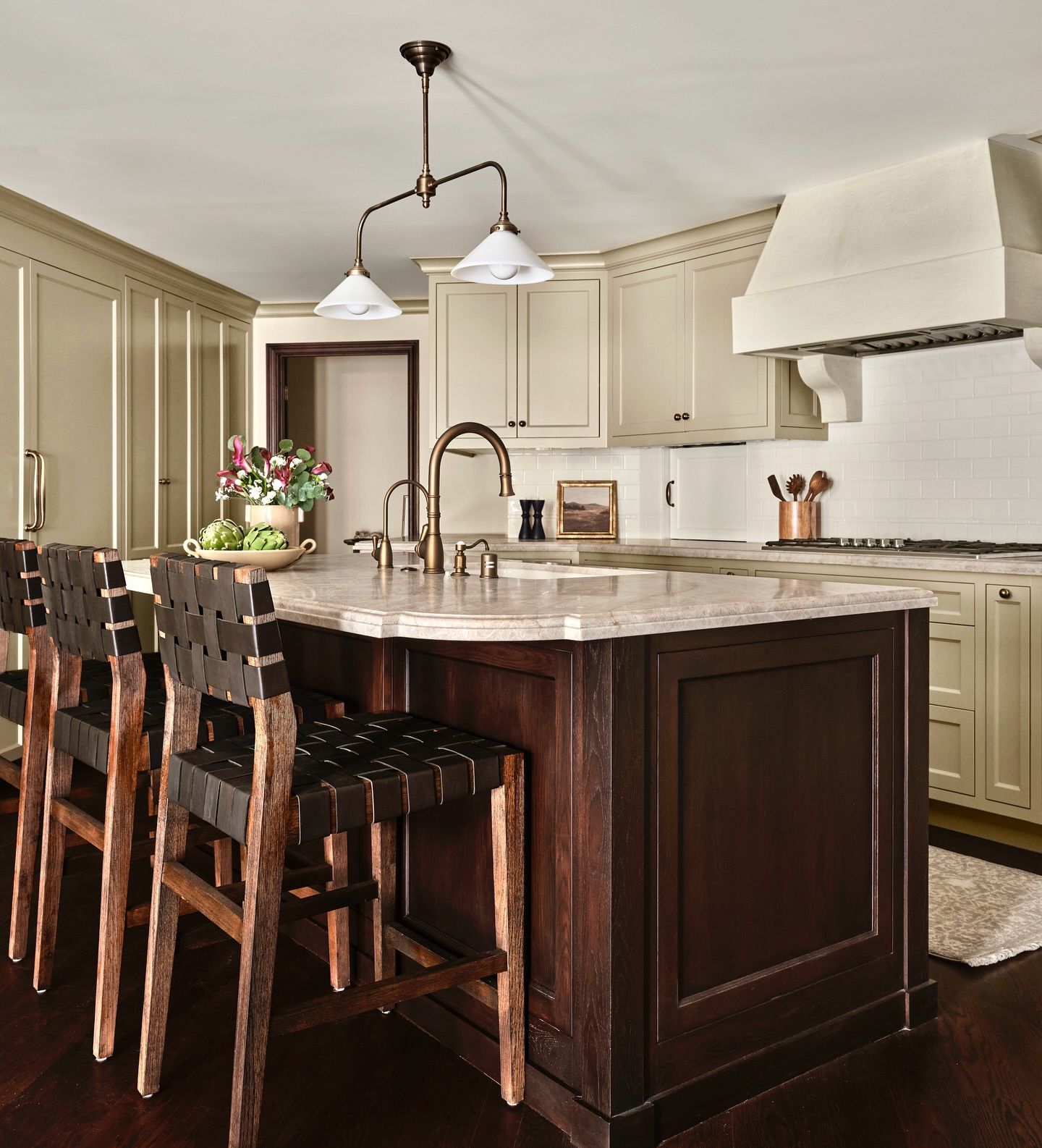 Kitchen with dark wood island, cream cabinets, and leather bar stools.