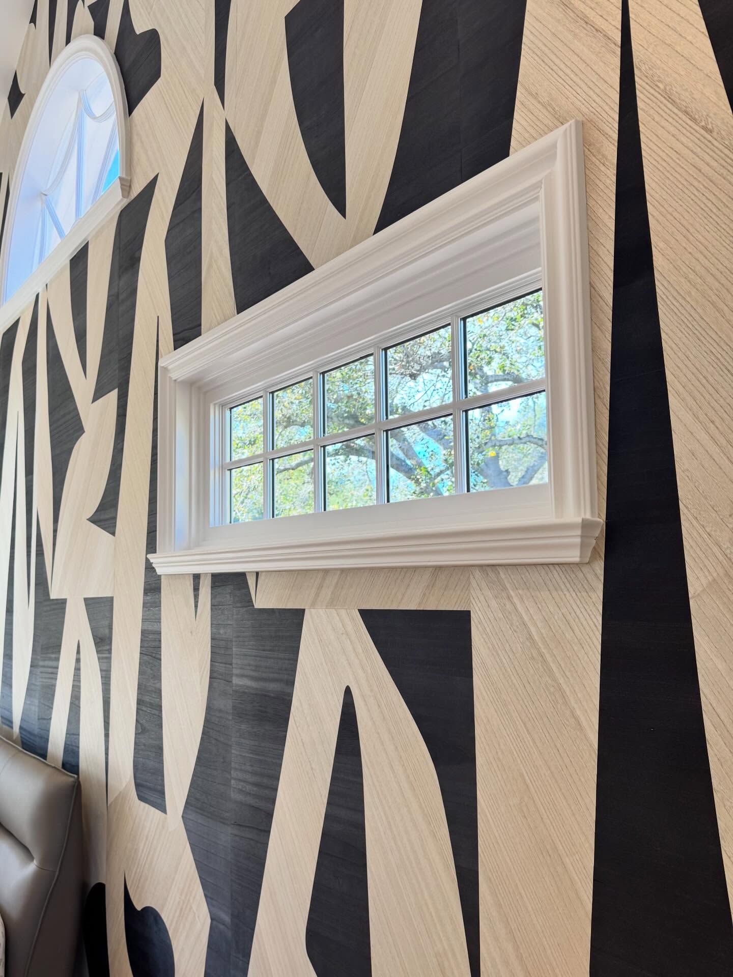 White framed window on a wall with a black and beige geometric pattern.