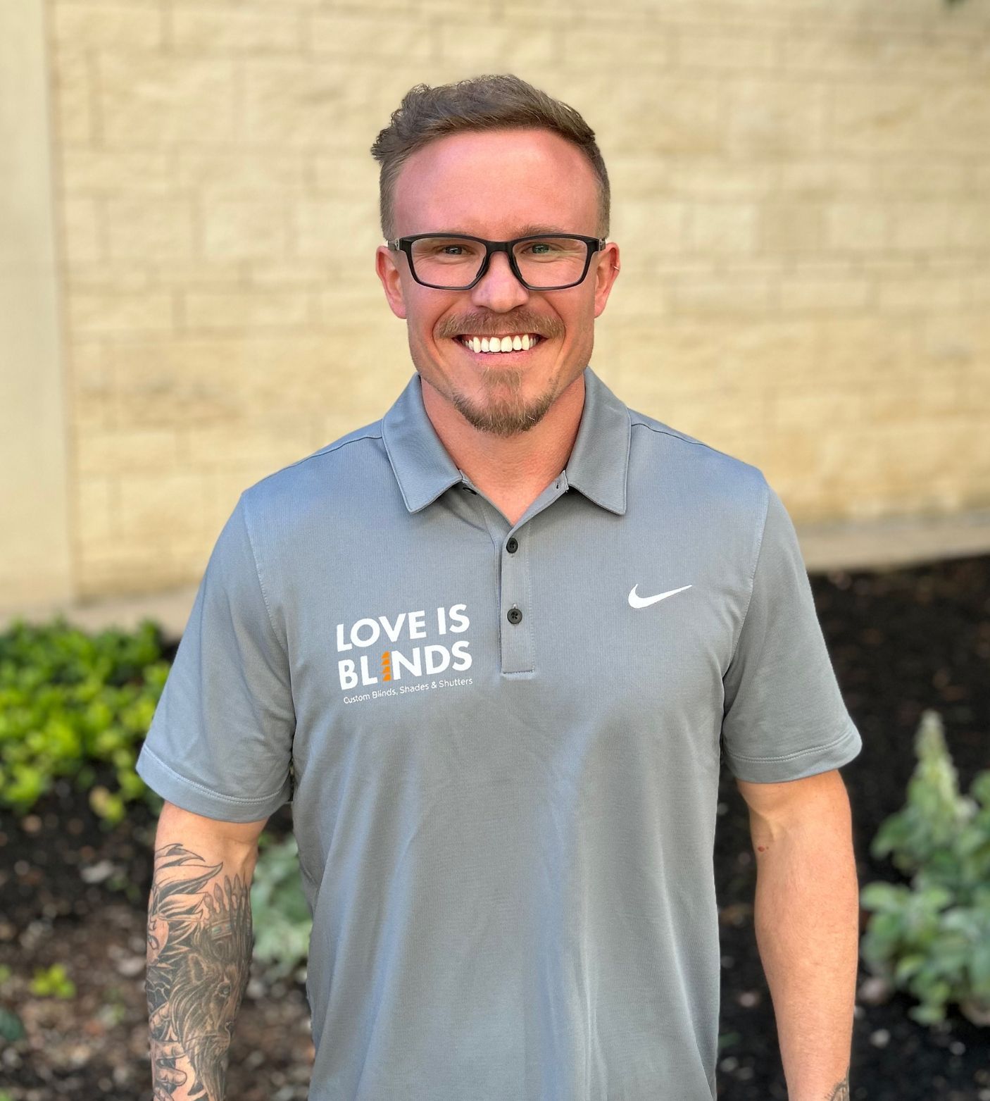 A man wearing glasses and a grey shirt that says love is blinds