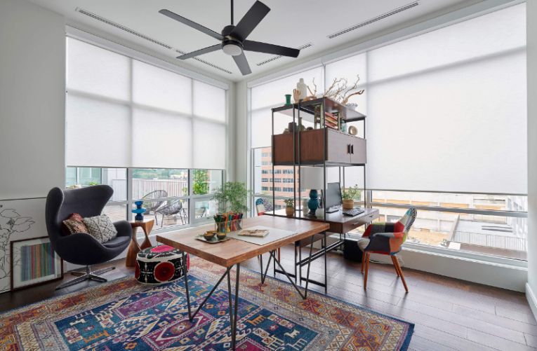 An office in a high rise has roller shades on the windows. 