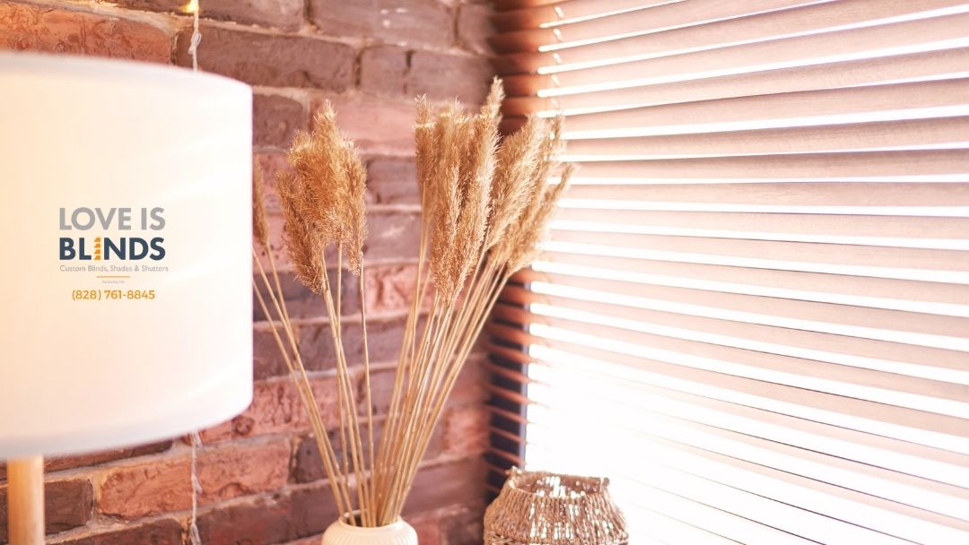 Lamp, wheat stalks in vase, and blinds against a brick wall.