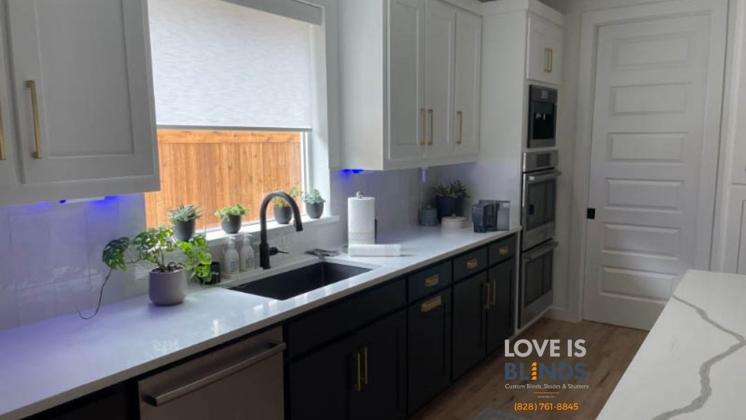 Modern kitchen with white countertops, black cabinets, gold hardware, and a built-in oven.