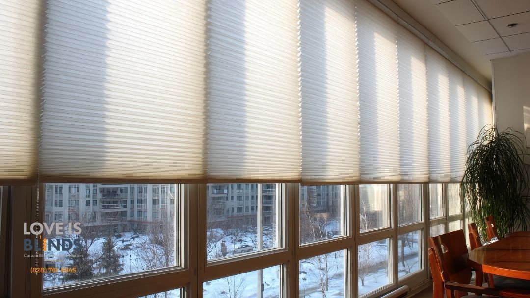 Honeycomb blinds over windows, filtering sunlight, revealing outdoor cityscape.