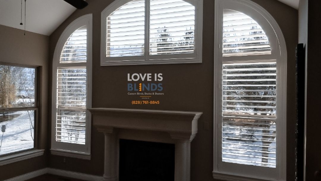 Living room with arched windows, blinds, fireplace, and snowy outdoor view.