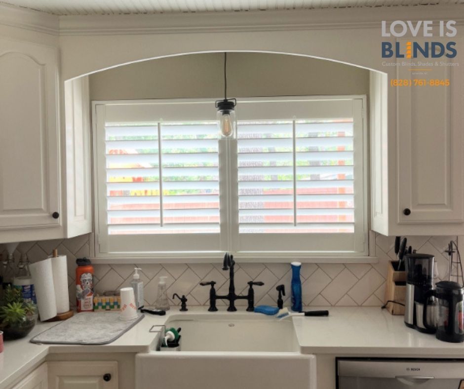 White kitchen window with shutters above a sink and countertop.