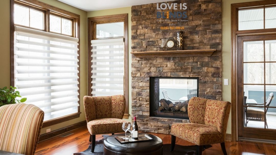 Living room with stone fireplace, two patterned chairs, and a window.