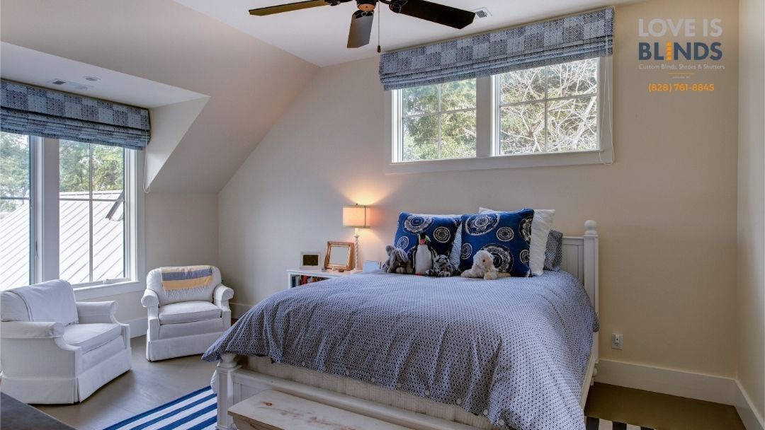 Bedroom with bed, two white armchairs, blue and white decor, and windows.