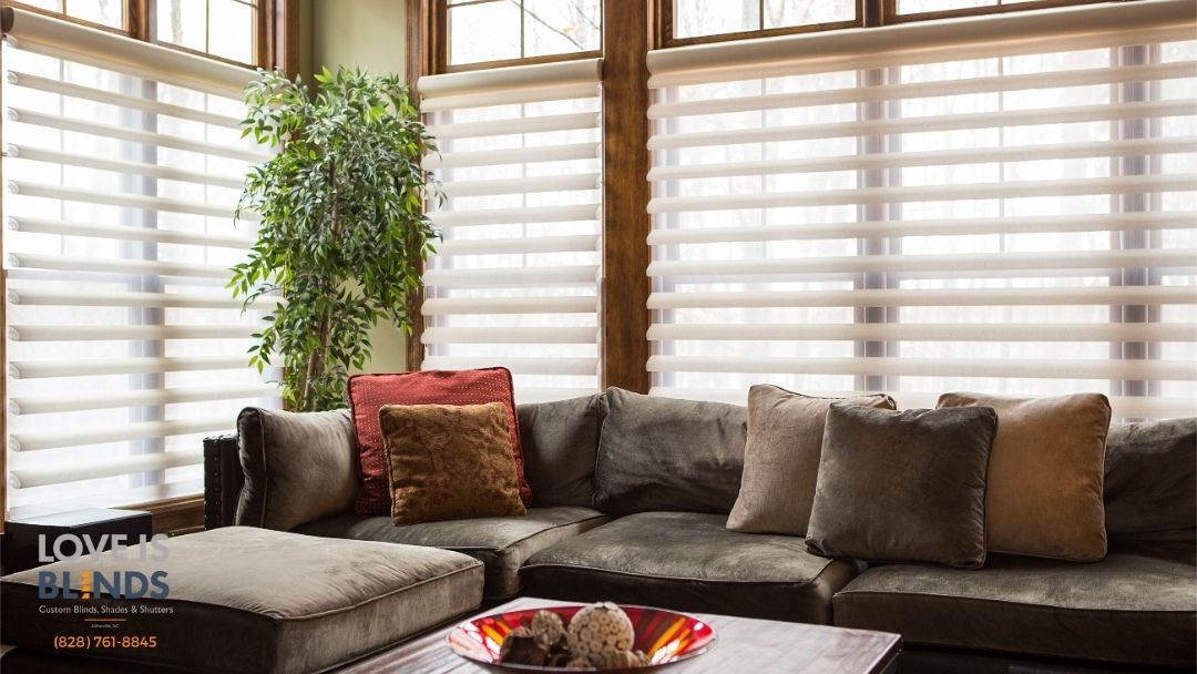 A modern living room with a brown sectional, layered blinds, and decorative pillows by a window.