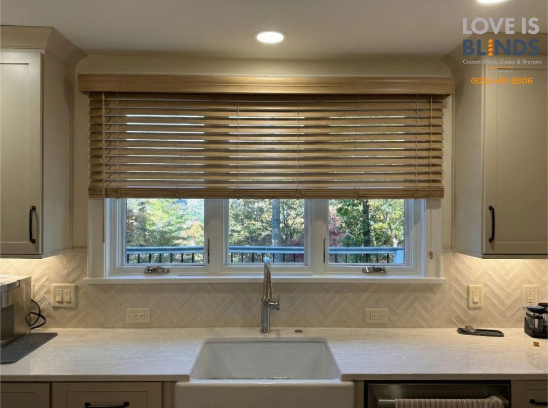 Kitchen window with beige woven blinds above a white farmhouse sink and backsplash.