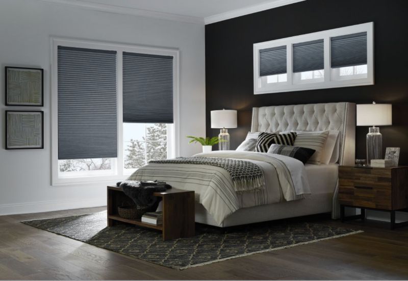 Modern gray bedroom with tufted bed, bedside lamps, and large windows with blinds