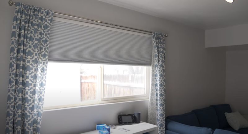 A bedroom window has colorful blue-patterned drapes. 