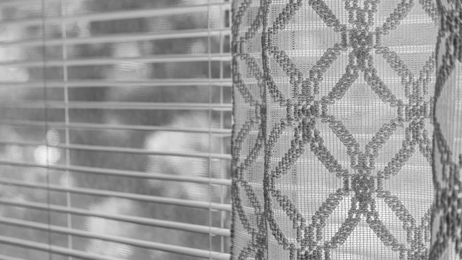 Close-up of blinds and patterned lace curtain; sunlight filters through.