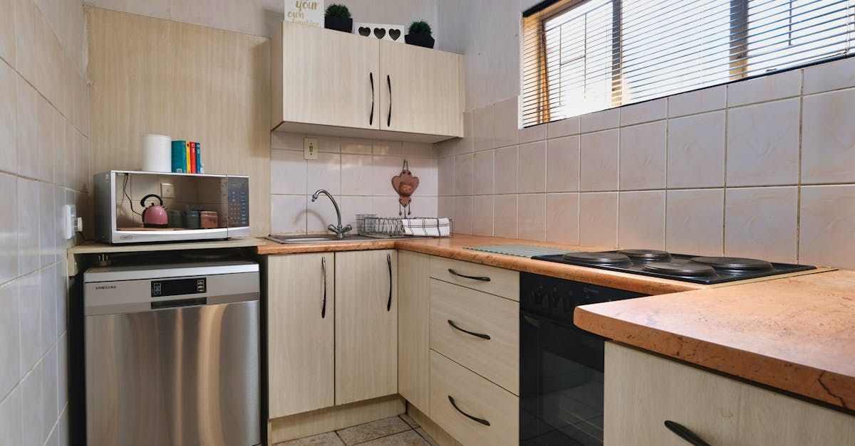 Small kitchen with off-white cabinets, stainless steel dishwasher, microwave, and gas stove.