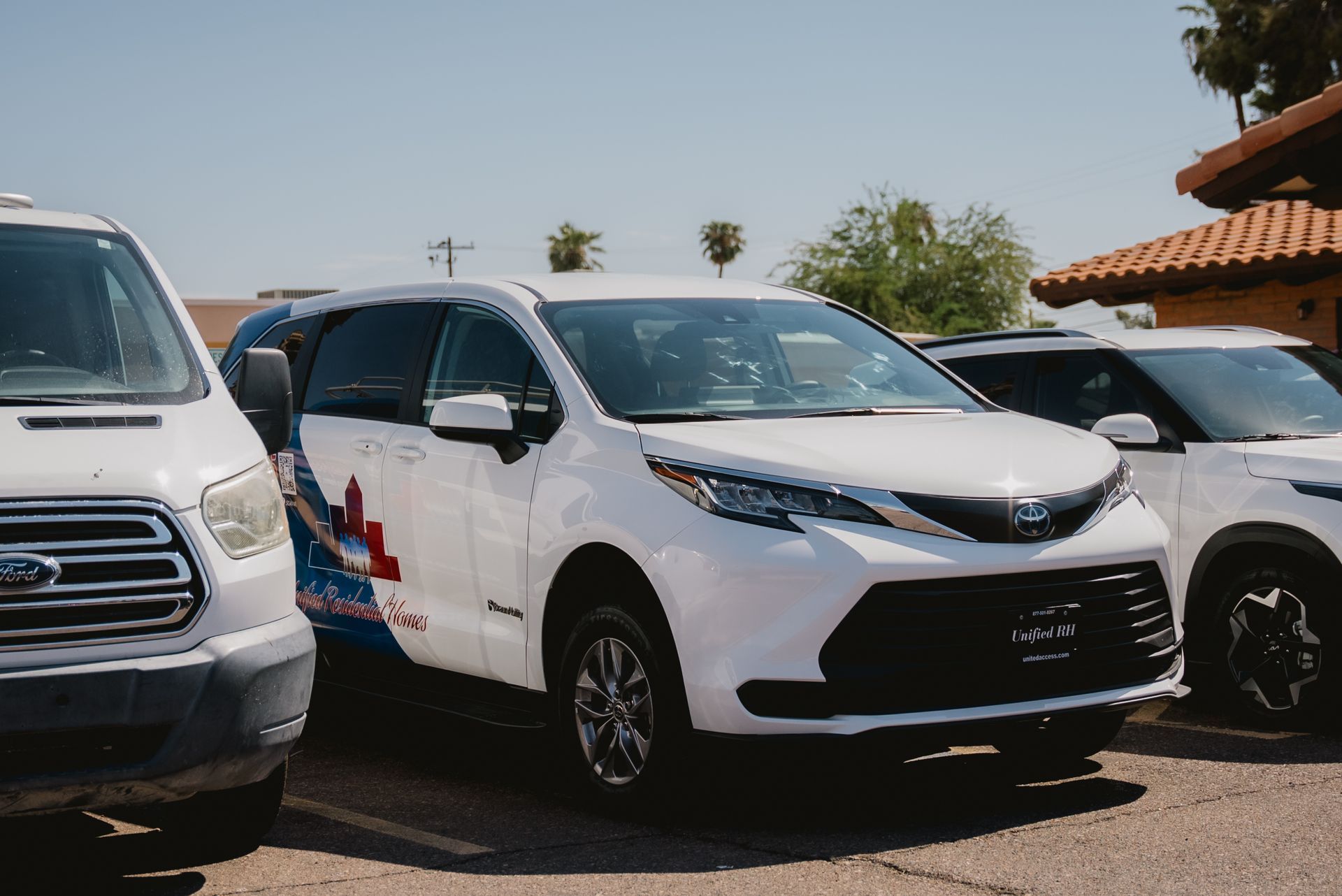 A row of white URH cars are parked next to each other in a parking lot.