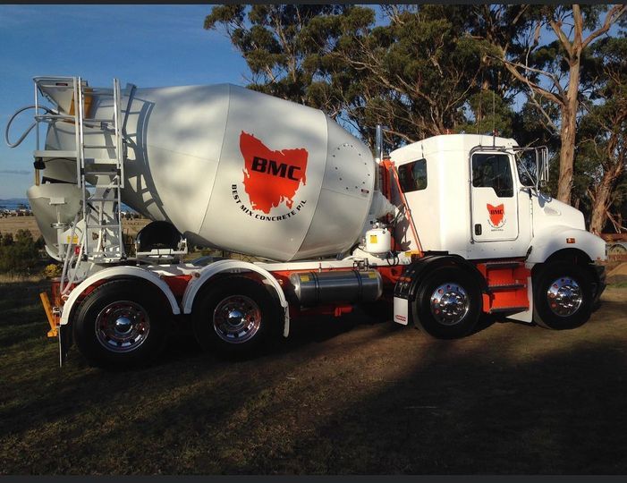 A concrete mixer truck is parked in a field