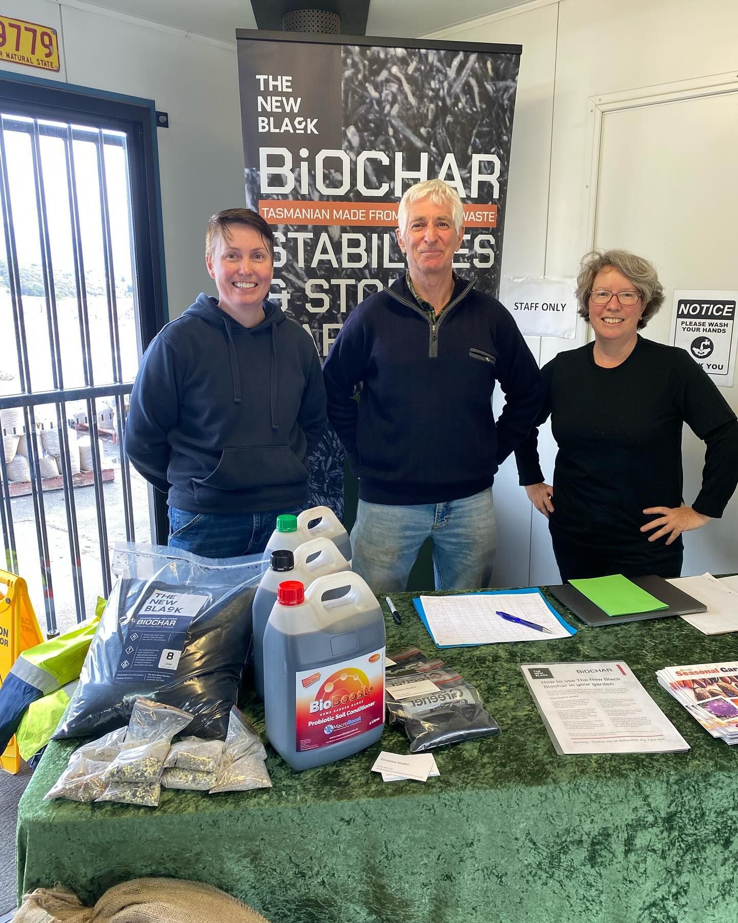 Three people are standing in front of a table in a room.