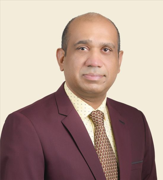 A man in a suit and tie is standing in front of a white background.