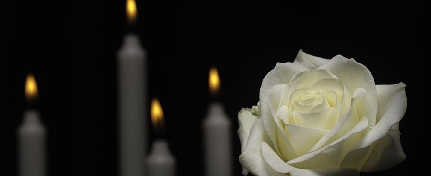 Una rosa bianca davanti a delle candele