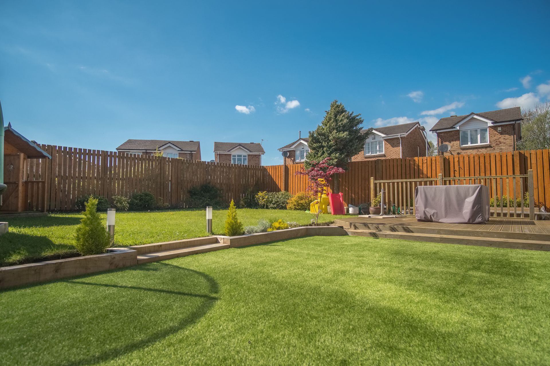 A backyard with a wooden fence and a lush green lawn.