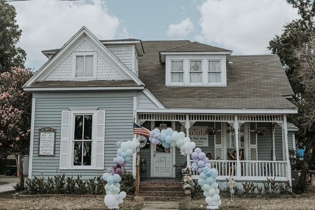 A light blue house with a porch decorated with balloons. An American flag is visible.