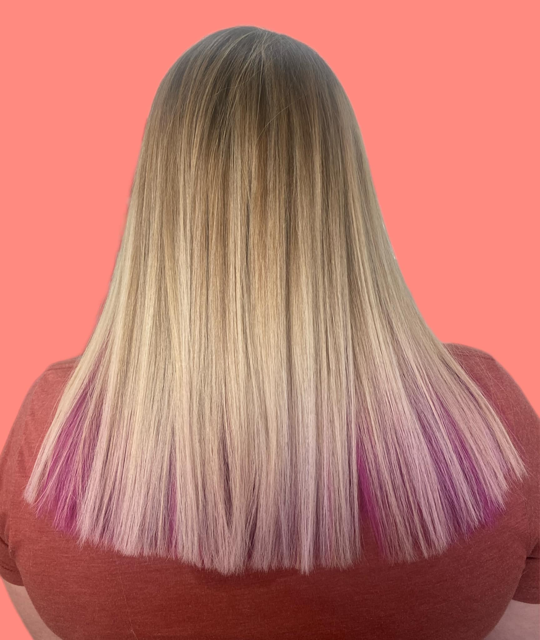Blonde hair with crimped texture and pink dip-dye, against a coral background.