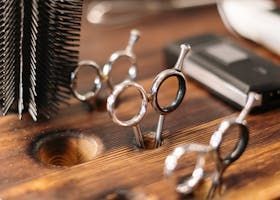 Hairdressing tools, including scissors and a brush, displayed in a wooden holder.