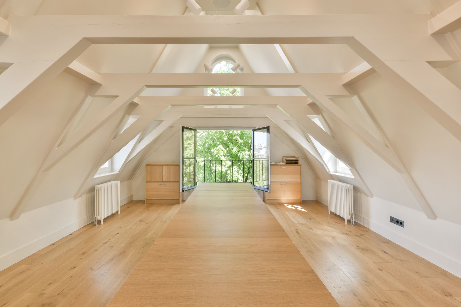 An empty attic with wooden floors and white walls.